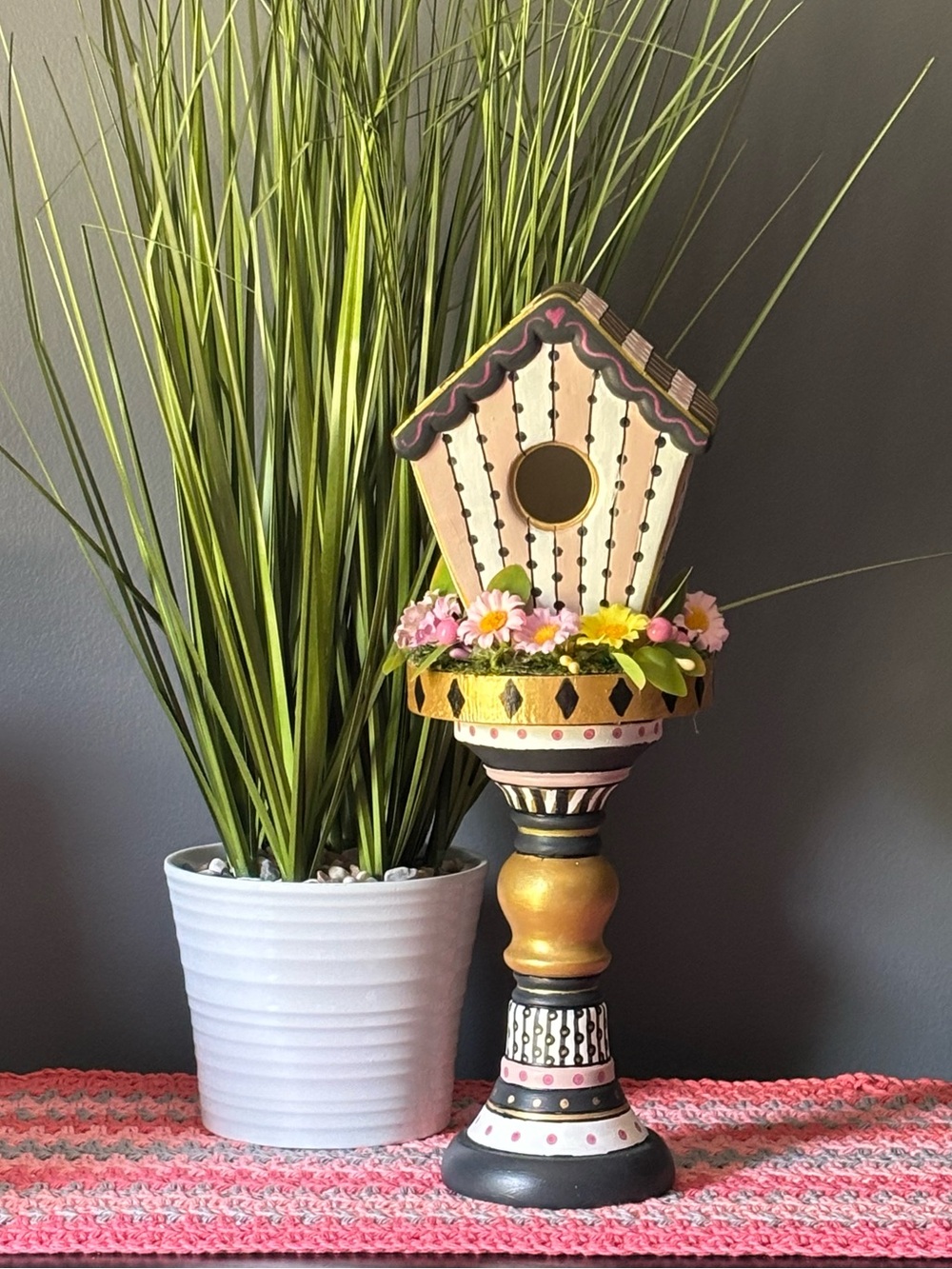 Whimsical hand painted birdhouse on pedestal.